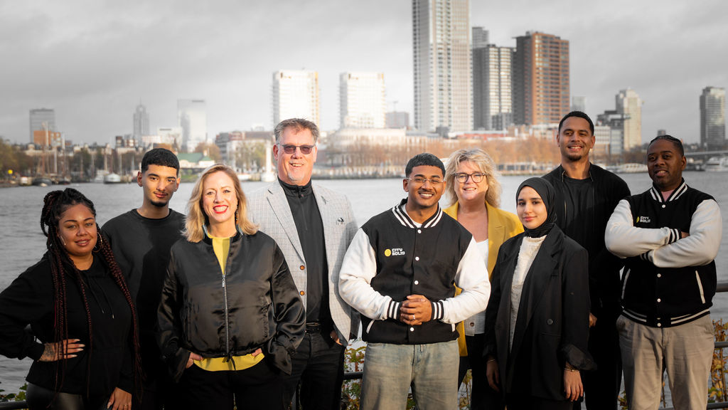 Team van City Solid Rotterdam aan de Maas met de Rotterdamse skyline op de achtergrond